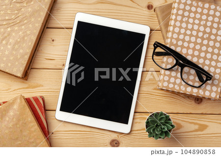 Top view of wooden table with white digital tablet with black screen on it 104890858