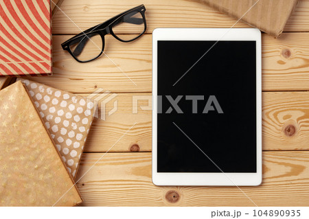 Top view of wooden table with white digital tablet with black screen on it 104890935