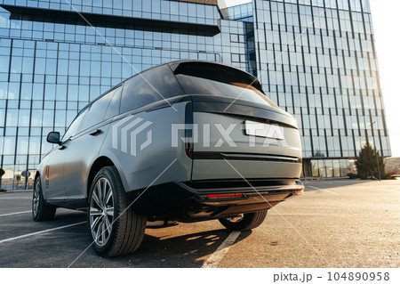 Luxury SUV car parked against a background of glass building Luxury SUV car parked against a background of glass building 104890958
