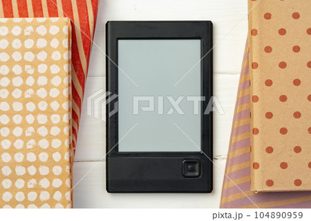 E-book reader device on background of paper books E-book reader device on background of paper books 104890959