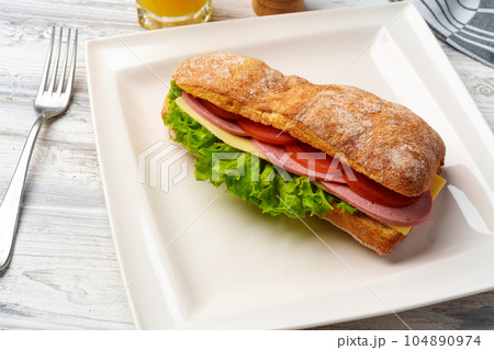 Sandwich with ham, cheese and vegetables on white plate on table 104890974