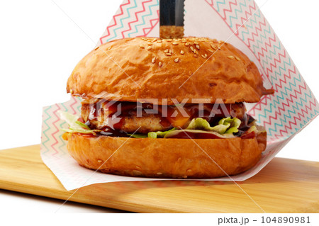 Delicious burger on wooden board isolated on white background Delicious burger on wooden board isolated on white background 104890981