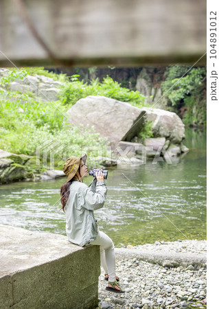 川原でバードウオッチングを楽しむ女性 104891012