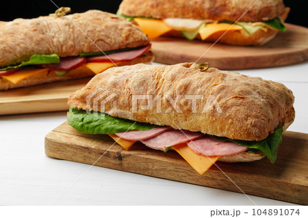 Chiabatta sandwich with ham and cheese on wooden board Chiabatta sandwich with ham and cheese on wooden board 104891074