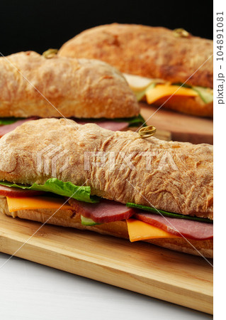 Chiabatta sandwich with ham and cheese on wooden board Chiabatta sandwich with ham and cheese on wooden board 104891081