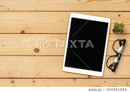 Top view of wooden table with white digital tablet with black screen on it Top view of wooden table with white digital tablet with black screen on it 104891084