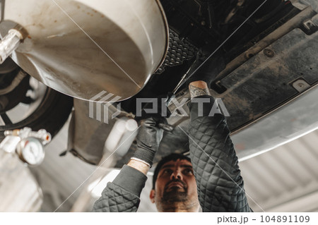 Car mechanic changing oil in a car service 104891109