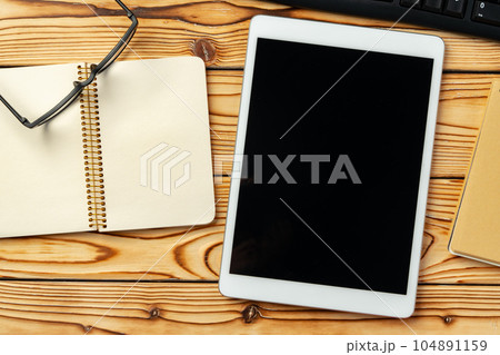 Top view of wooden table with white digital tablet with black screen on it 104891159