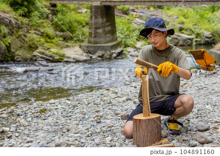 キャンプで薪割りをする男性 104891160