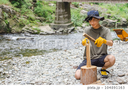 キャンプで薪割りをする男性 104891163