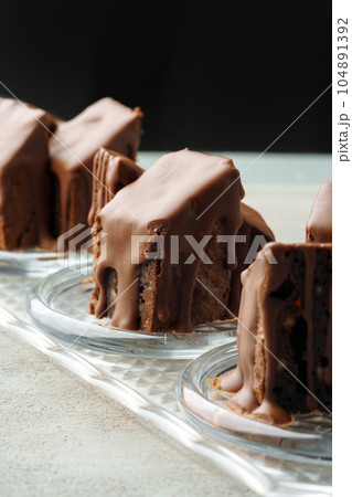 Chocolate sponge cake coated with chocolate sauce on glass plate 104891392