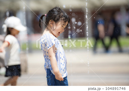 広場の噴水で水遊びしている3歳の女の子 104891746