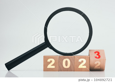 2023 wood block with magnifying glass on white background. 2023 wood block with magnifying glass on white background. 104892721