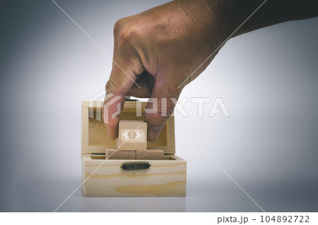 Hand pick wood block with us dollar icon in the treasure box. Hand pick wood block with us dollar icon in the treasure box. 104892722