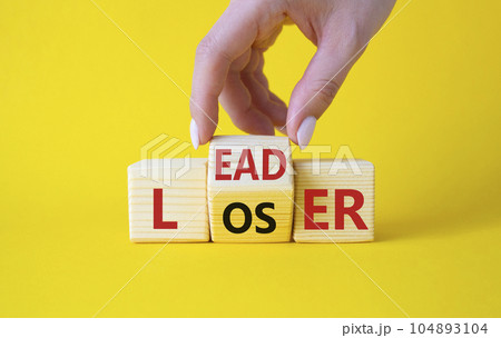 Leader vs Loser symbol. Businessman hand turns wooden cubes and changes the word Loser to Leader. Beautiful yellow background. Leader vs Loser and business concept. Copy space 104893104