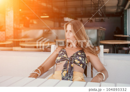 Happy woman portrait in cafe. Boho chic fashion style. Outdoor photo of young happy woman with long hair, sunny weather outdoors sitting in modern cafe. 104893332