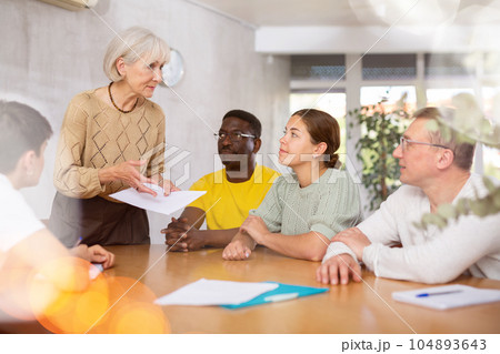 Group of multinational people discussing documents at table 104893643