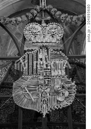 Grayscale shot of an art sculpture made of human bones in the Sedlec Ossuary in Kutna Hora, Czech Republic Grayscale shot of an art sculpture made of human bones in the Sedlec Ossuary in Kutna Hora, Czech Republic 104893680