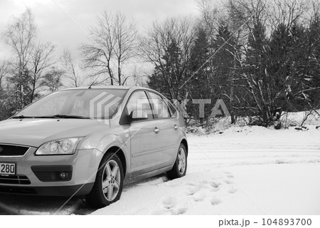 Gray car driving on a trail through a snowy white forest 104893700
