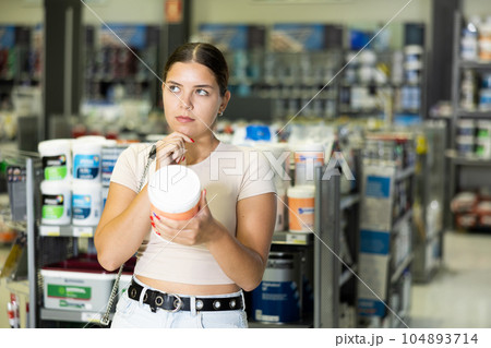 Thoughtful young girl choosing paint in hardware store 104893714