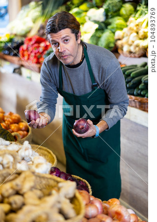 Adult man selling onions in shop 104893769