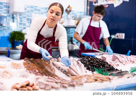 Positive saleswoman demonstrating calamary in fish store 104893956