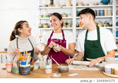Two young women and young man making pottery Two young women and young man making pottery 104894375