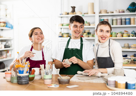 Joyous young man and women sculpting handmade cups Joyous young man and women sculpting handmade cups 104894480