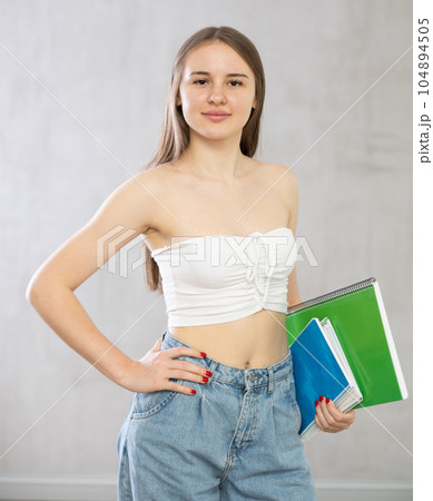 Young woman with stack of notebooks posing in studio 104894505