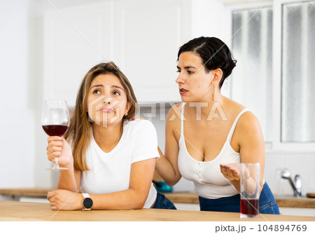 Woman consoling the depressed woman at table in kitchen Woman consoling the depressed woman at table in kitchen 104894769