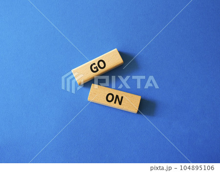 Go on symbol. Wooden blocks with words Go on. Beautiful blue background. Business and Go on concept. Copy space. 104895106