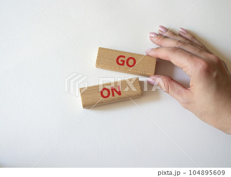 Go on symbol. Wooden blocks with words Go on. Businessman hand. Beautiful white background. Business and Go on concept. Copy space. Go on symbol. Wooden blocks with words Go on. Businessman hand. Beautiful white background. Business and Go on concept. Copy space. 104895609
