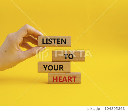 Listen to your heart symbol. Concept word Listen to your heart on wooden blocks. Beautiful yellow background. Businessman hand. Business and Listen to your heart concept. Copy space Listen to your heart symbol. Concept word Listen to your heart on wooden blocks. Beautiful yellow background. Businessman hand. Business and Listen to your heart concept. Copy space 104895868