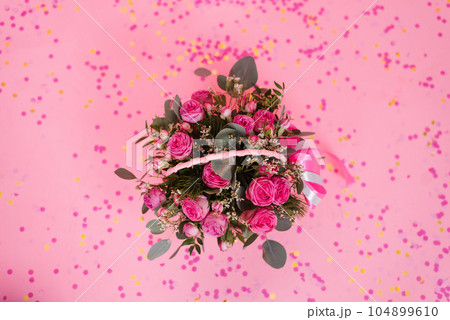 Romantic bouquet of pink roses and eucalyptus in a basket on a pink background with confetti. Birthday gift, Women's Day, Mom's Day, Valentine's Day Romantic bouquet of pink roses and eucalyptus in a basket on a pink background with confetti. Birthday gift, Women's Day, Mom's Day, Valentine's Day 104899610