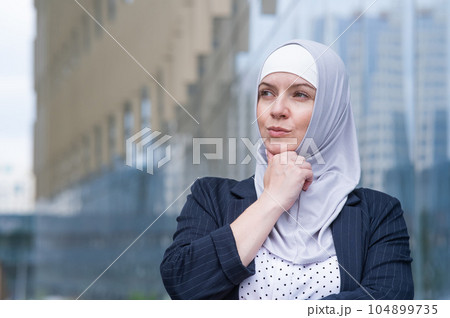Portrait of pensive business woman in hijab and suit outdoors. Portrait of pensive business woman in hijab and suit outdoors. 104899735
