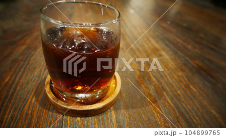 Transparent Glasses with sweet drinks inside with colorful drink, with shadow and table background with ice cubes on a bar restaurant 104899765