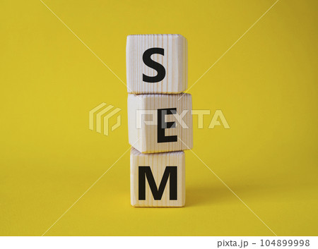 SEM - Search Engine Marketing symbol. Wooden cubes with words SEM. Beautiful yellow background. Business and SEM concept. Copy space. 104899998