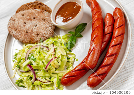 sausages with coleslaw salad, bbq sauce on plate sausages with coleslaw salad, bbq sauce on plate 104900109