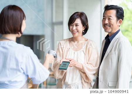 カフェでスマホ決済するミドルの夫婦と店員 カフェでスマホ決済するミドルの夫婦と店員 104900941