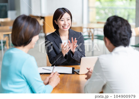 カフェでミドルの夫婦に商談するビジネスウーマン カフェでミドルの夫婦に商談するビジネスウーマン 104900979