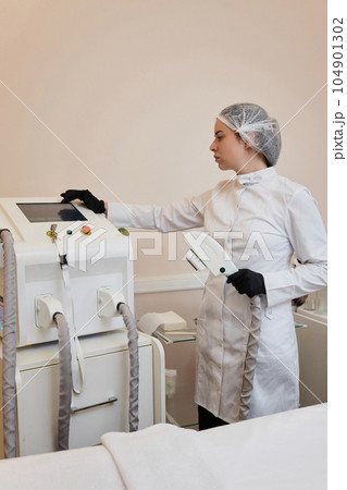 cosmetologist with laser, hair removal with modern equipment cosmetologist with laser, hair removal with modern equipment 104901302