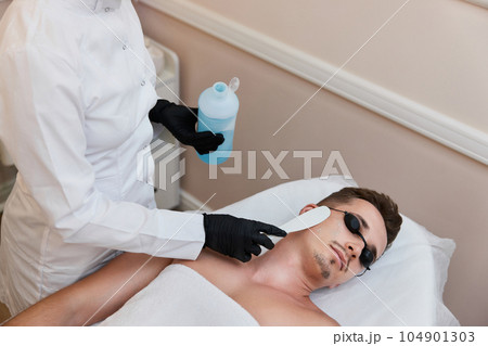 Young man receiving epilation in beauty center. laser hair removal procedure Young man receiving epilation in beauty center. laser hair removal procedure 104901303