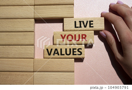 Live your values symbol. Concept words 'Live your values' on wooden blocks. Beautiful pink background. Businessman hand. Business and Live your values concept. Copy space. Live your values symbol. Concept words 'Live your values' on wooden blocks. Beautiful pink background. Businessman hand. Business and Live your values concept. Copy space. 104903791