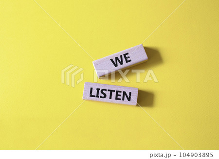 We listen symbol. Wooden blocks with words We listen. Beautiful yellow background. Business and We listen concept. Copy space. 104903895