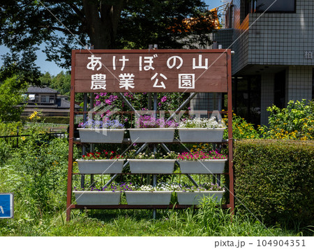 あけぼの山農業公園　本館前の駐車場に置かれた看板とプランター 104904351