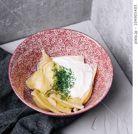 Dumplings with cottage cheese with sour cream on a plate Dumplings with cottage cheese with sour cream on a plate 104905485