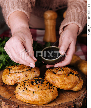 woman sprinkles seeds fresh twisted bun with sesame seeds woman sprinkles seeds fresh twisted bun with sesame seeds 104906214