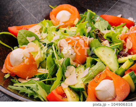 Salmon salad with mozzarella, tomato, cucumber on bowl 104906818