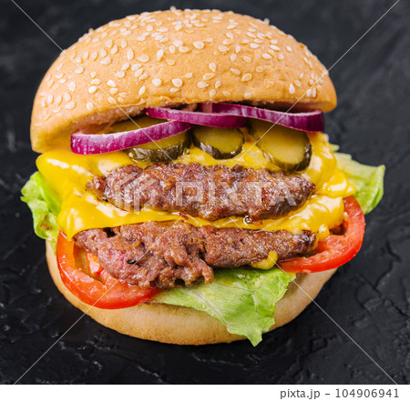 Double patty burger with pickles on black stone Double patty burger with pickles on black stone 104906941