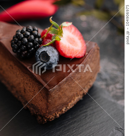Delicious chocolate cake decorated with fresh berries on wooden table 104906975
